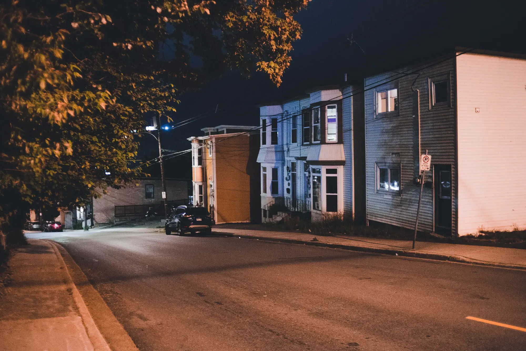 A residential street at night, houses lit by a single streetlight